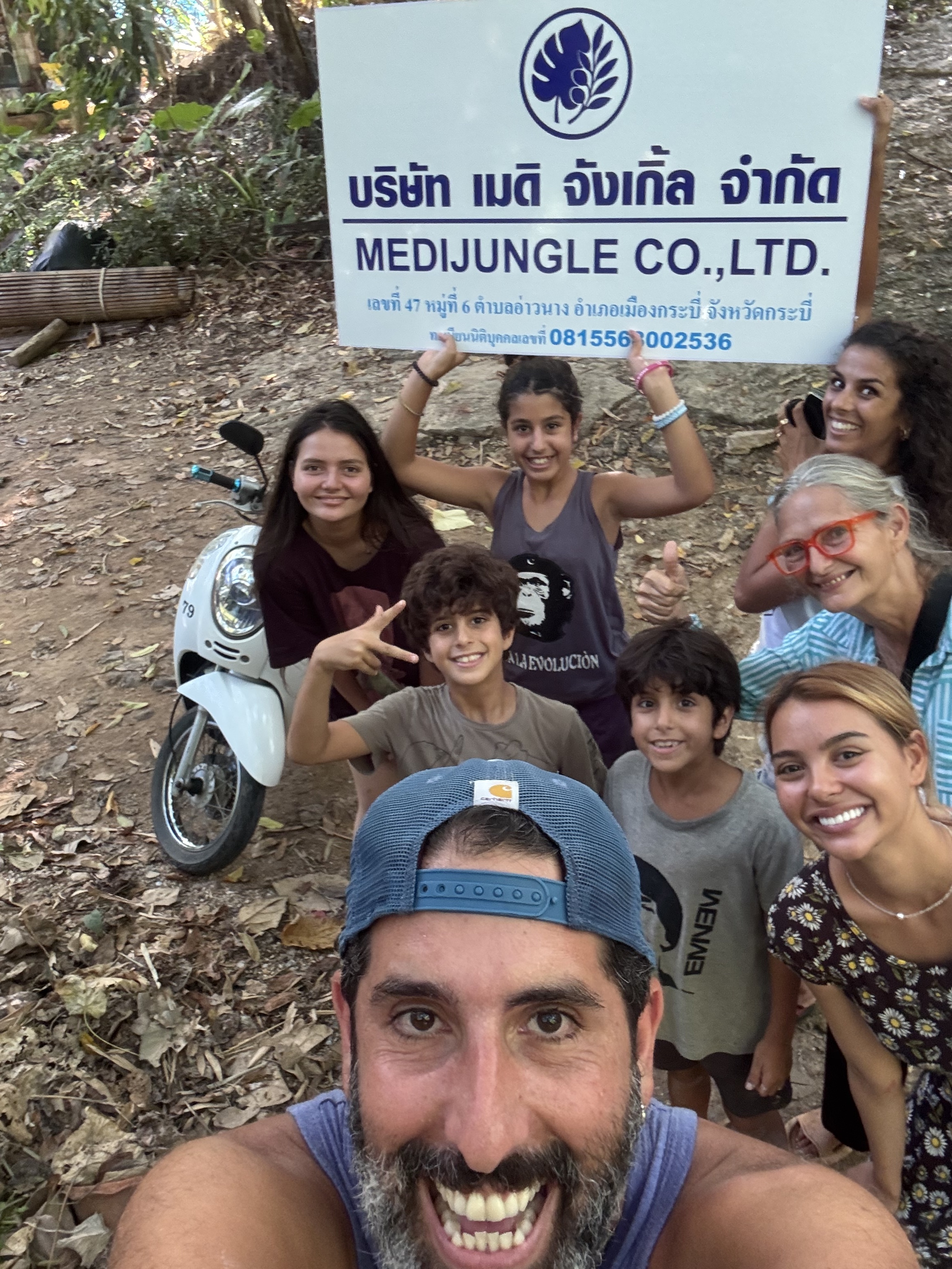 Shay with his family and the Giant Catfish Farm friends in front of the official MediJungle Co., Ltd. business sign in Krabi