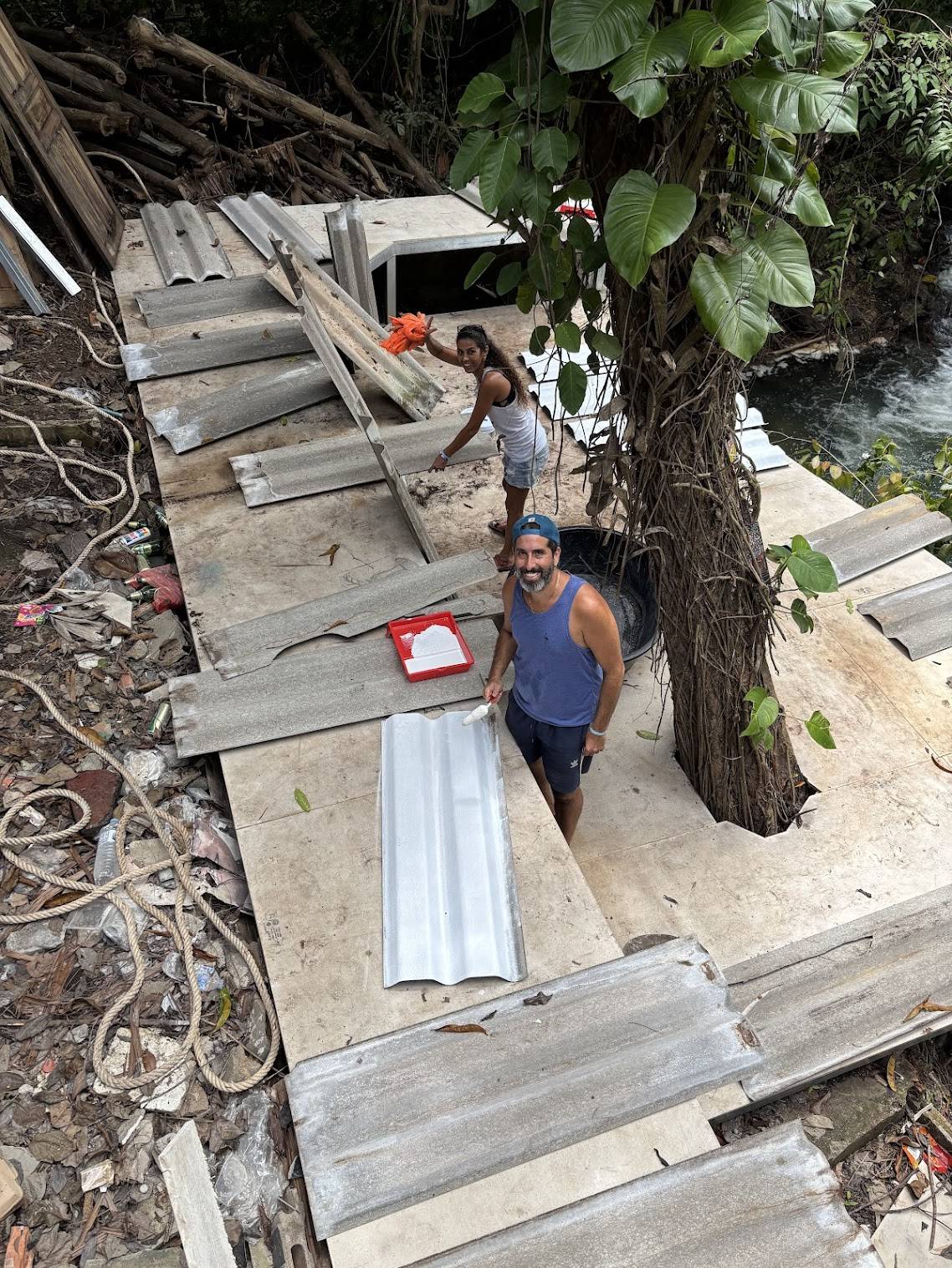 Shay and Shani painting corrugated metal roof panels during MediJungle construction